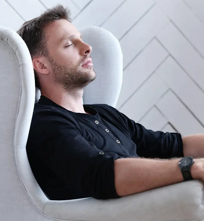 Homme fermant les yeux dans un fauteuil. Séance de Sophrologie